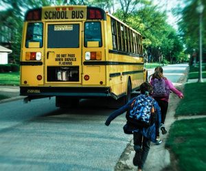 Kids running after school bus